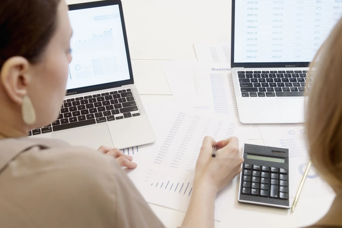 Illustrative stock photograph of colleagues checking printed charts beside a laptop