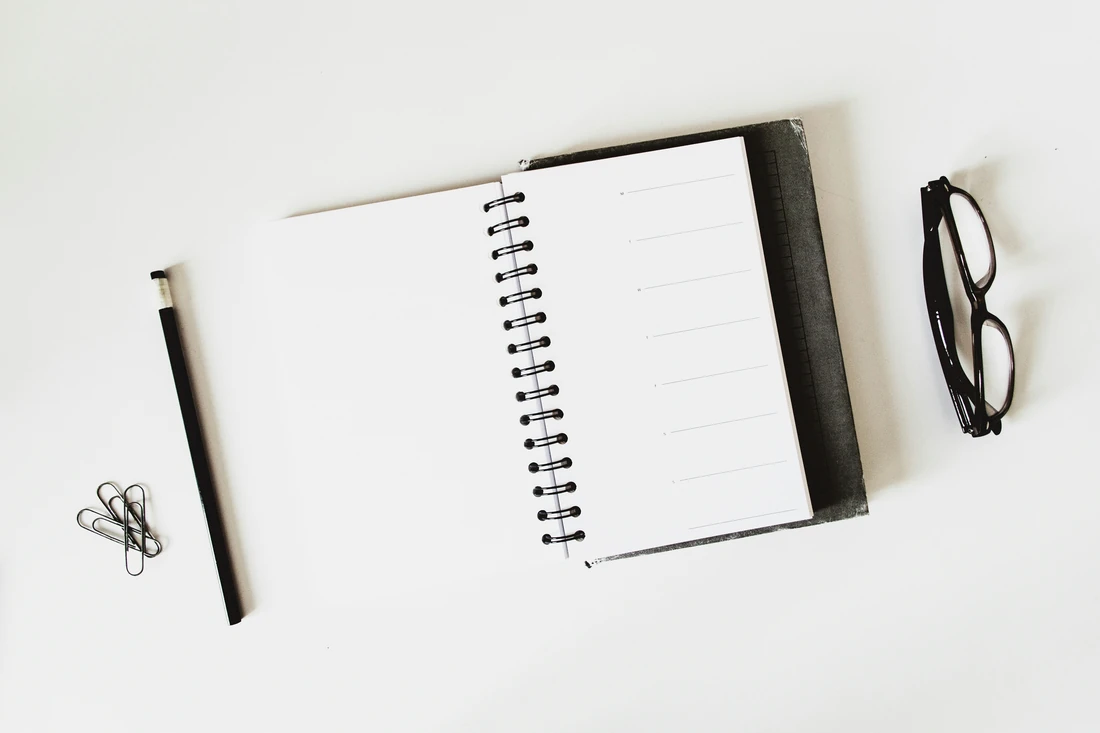 Open notebook with a pen and glasses, illustrating preparation of enquiry-form acceptance tests