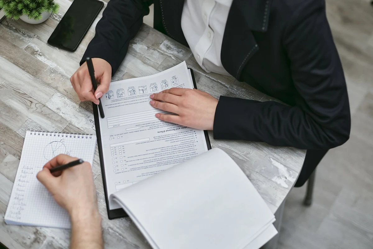 Two people recording notes while reviewing documents at a desk