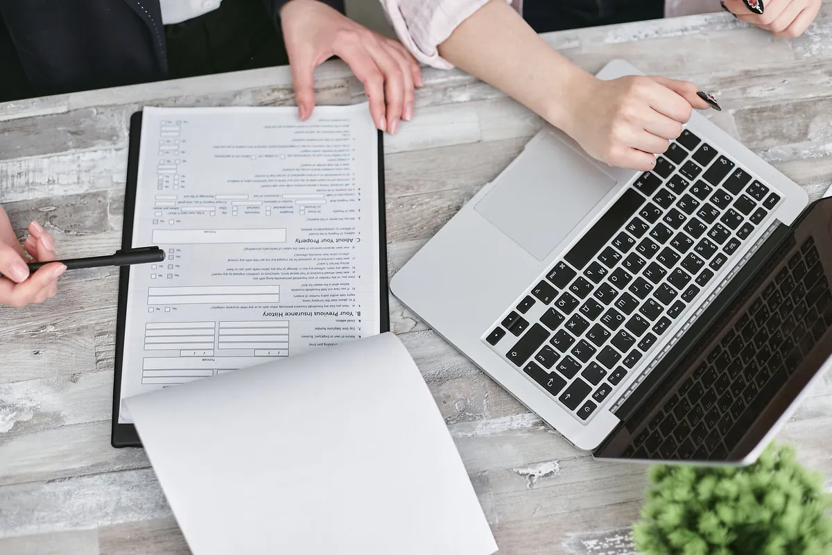 Hands comparing a printed document with a laptop during an illustrative content review