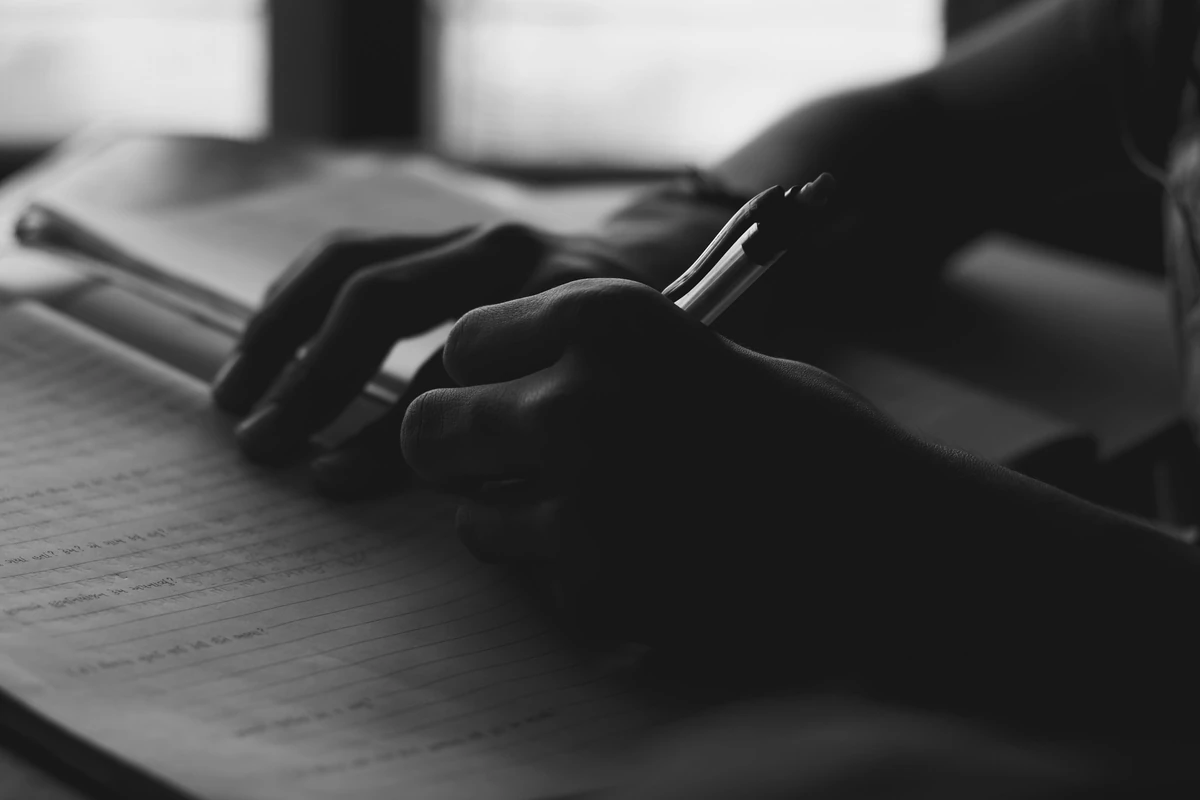 Illustrative photograph of a hand writing clear review notes in a notebook