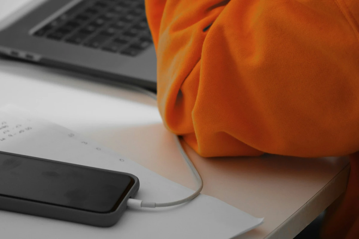 Illustrative desk photograph with a notebook, phone and laptop for recording specific design observations