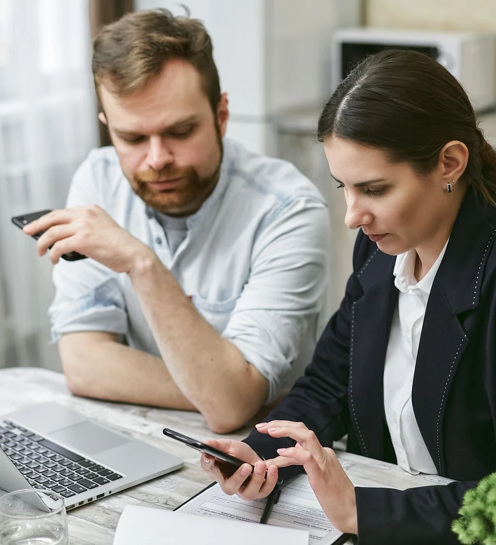 Professionals reviewing mobile and laptop use together, illustrative stock photography