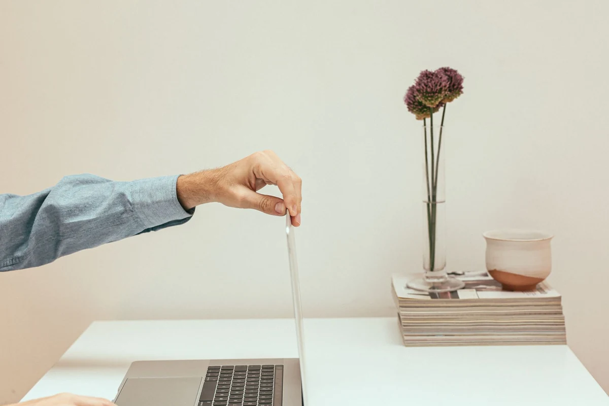 Person closing a laptop at a desk, illustrating why ending work and explicitly signing out are different actions