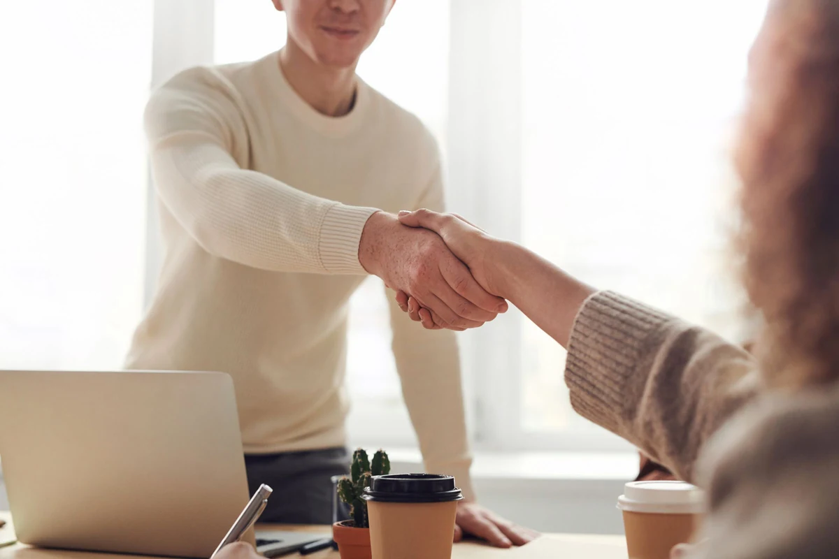 Two professionals shaking hands across an office table, illustrating a clearly agreed support relationship