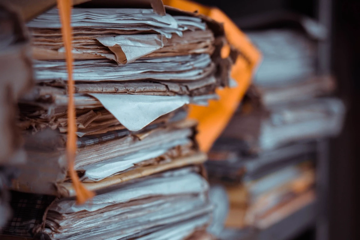 Paper records stacked on shelves, illustrating why a collection needs clear organisation before retrieval